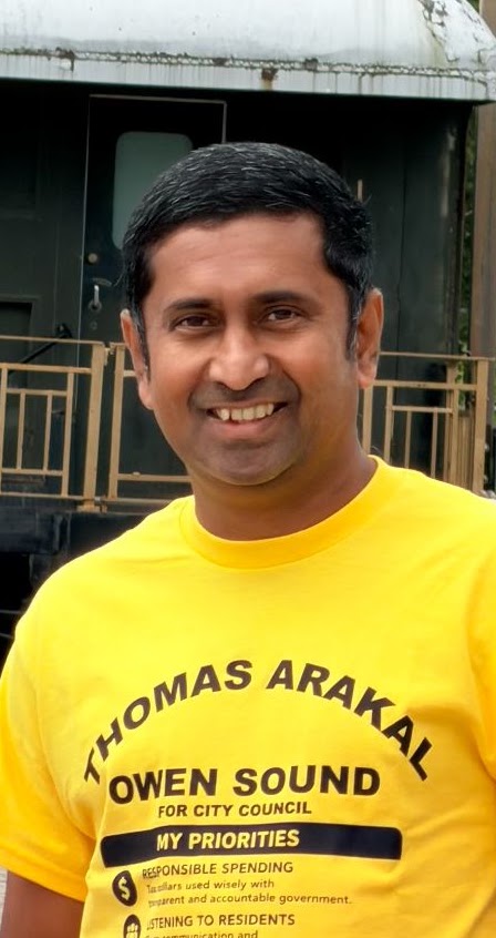 Thomas Arakal wearing a campaign shirt outside in Owen Sound